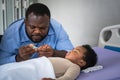 Nigerian father is using a nail clipper for her 10-month-old baby newborn son who is sleeping on a patient bed Royalty Free Stock Photo