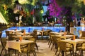 Night cafe, empty tables served for dinner, candles, lights, by the pool in the garden with palm trees and flowers, evening rest Royalty Free Stock Photo