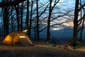 Night camp in the forest. light in the camping tent and portable chairs and aluminum table. Cold autumn. concept of vacation and