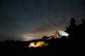 Tourists near campfire and tent under night starry sky Royalty Free Stock Photo
