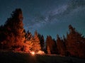 Pair vacationers at bonfire in mountains under starry sky. Royalty Free Stock Photo