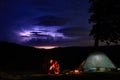 Night camping in the mountains. Couple tourists have a rest at a campfire near illuminated tent Royalty Free Stock Photo