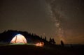 Friends resting beside camp, campfire under night starry sky Royalty Free Stock Photo