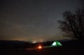 Night camping in the mountains. Hikers having a rest in tourist tent under starry sky near campfire Royalty Free Stock Photo