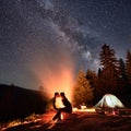 Night camping in mountains near forest with campfire and tourist tent. Royalty Free Stock Photo