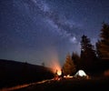 Night camping in mountains near forest with campfire and tourist tent. Royalty Free Stock Photo