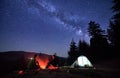 Night camping in mountains near forest with campfire and tourist tent. Royalty Free Stock Photo