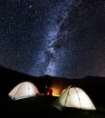 Couple tourists near campfire and tents under night sky full of stars and milky way Royalty Free Stock Photo