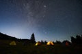 Night camping in mountains under starry sky.