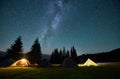 Night camping in mountains under starry sky.