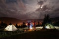 Night camping. Romantic couple standing and holding hands lifting up