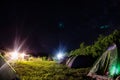 Night camping under starry sky. Glowing tourist tent, under beautiful evening sky full of stars and Milky way, city Royalty Free Stock Photo