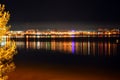 Night city landscape. Glowing lights on the river Bank.