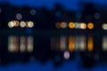 Night city lights are reflected in water. Lights look like color people silhouettes. Blurred image
