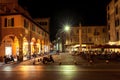 Night city with restaurants near dark road and cafe with visitors