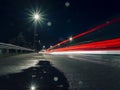 Night city scene with puddle by a road and car light trail. Dark night sky. Town traffic