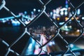 Night city seen behind a grid fence