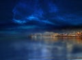 Night city blurred light on horizon at sea blue water wave starry sky