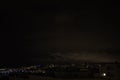 Night city skyline. Top aerial panoramic view of modern city from tower rooftop. Road junction traffic. Heavy clouds on the sky