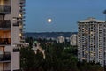 Night city view with full yellow moon raising over