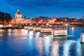 cityscape with illuminated academic building Institut de France and pedestrian bridge with lanterns over the river Seine in