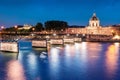 Night cityscape with illuminated academic building Institut de France and pedestrian bridge with lanterns over the river Seine in