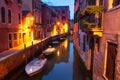 Night cityscape of Venice, Italy. Boats and houses on water canal illuminated lights of city lanterns Royalty Free Stock Photo