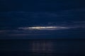 Night Clouds Over the Water. The Light from the Full Blue Moon Breaks Brightly Through the Clouds and Rises over the Calm Ocean, Royalty Free Stock Photo