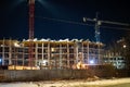 Night construction site at dusk. Construction crane in night illumination, the construction of a multi-storey modern residential Royalty Free Stock Photo