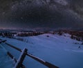 Night countryside hills, groves and farmlands in winter remote alpine mountain village, and starry sky with Milkyway above.