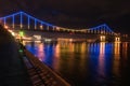Night european city in colorful lights and reflection in water, Kiev, Ukraine. Pedestrian bridge across the Dnieper river Royalty Free Stock Photo