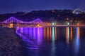 Night european city in colorful lights and reflection in water, Kiev, Ukraine. Pedestrian bridge across the Dnieper river Royalty Free Stock Photo