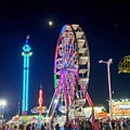 Night at the fair. Colorful neon lights on the carnival rides. Large ferris wheel.