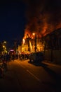 Night fire in apartment building, firefighters struggle with flame, silhouettes of unrecognizable people stand around