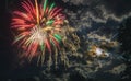 Night fireworks different colors on a night sky with moon and clouds