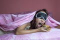 Night gluttony theme, woman with sleep mask on bed eating a piece of pie