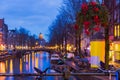 Night illumination of Amsterdam canal and bridge with typical dutch houses, boats and bicycles. Royalty Free Stock Photo