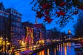 Night illumination of Amsterdam canal and bridge with typical dutch houses, boats and bicycles. Royalty Free Stock Photo