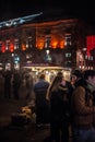 NIght image of man selling marrons chauds roasted chestnuts and pedestrians people