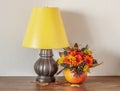 Night Lamp and Flowers in a Pumpkin on a Wooden Dresser.