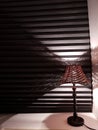 night lamp on a white windowsill against a background of black blinds, conceptual Reflection