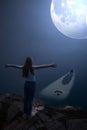 Night landscape of Cape Roca and Atlantic ocean in Portugal with a huge moon in the sky. A rear view of a girl standing on the