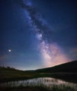 Night landscape with colorful Milky Way and light at mountains. Starry sky with hills at summer. Beautiful Universe. Lake in front Royalty Free Stock Photo