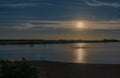 Night landscape with a full moon over the river. The beach is illuminated by the moon. The moon is reflected in the water. Royalty Free Stock Photo