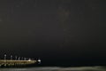 Small pleasure boat moored to a pier near the sea coast. Starry night sky over the sea Royalty Free Stock Photo