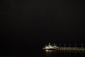 Small pleasure boat moored to a pier near the sea coast. Starry night sky over the sea Royalty Free Stock Photo