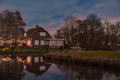 Night landscape with starry sky in the Dutch village of Streefkerk. Houses with bright light reflecting in the shine of the water