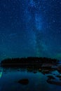 night landscape with a starry sky over sea water with stones and forest. Astrophotography with many stars, Milky Way Royalty Free Stock Photo