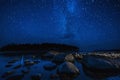 night landscape with a starry sky over sea water with stones and forest. Astrophotography with many stars, Milky Way Royalty Free Stock Photo