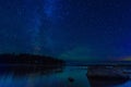 night landscape with a starry sky over sea water with stones and forest. Astrophotography with many stars, Milky Way Royalty Free Stock Photo